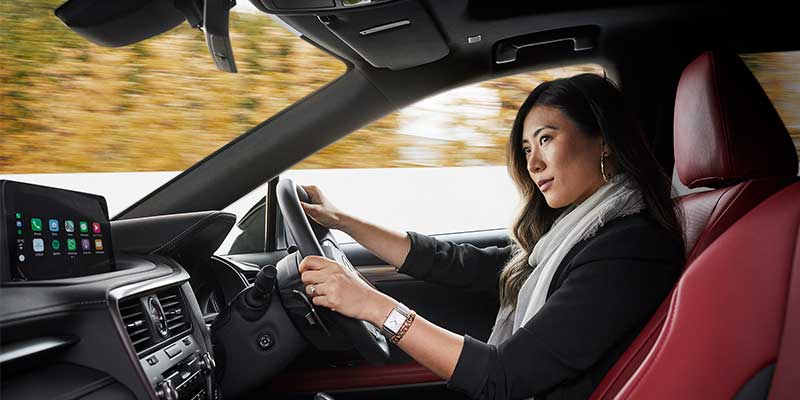 A female in the drivers seat of a Lexus