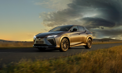 Lexus RZ drives on an Australian countryside road, away from a storm brewing in the far distance.