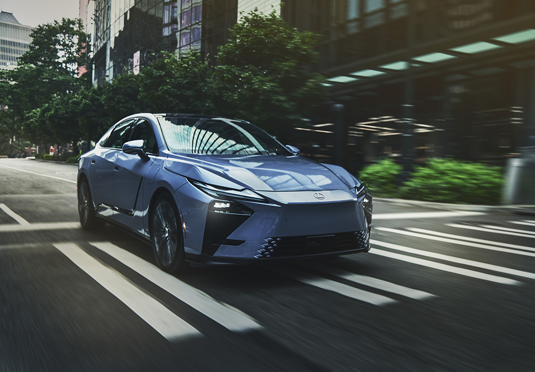 A blue Lexus ES drives through a city