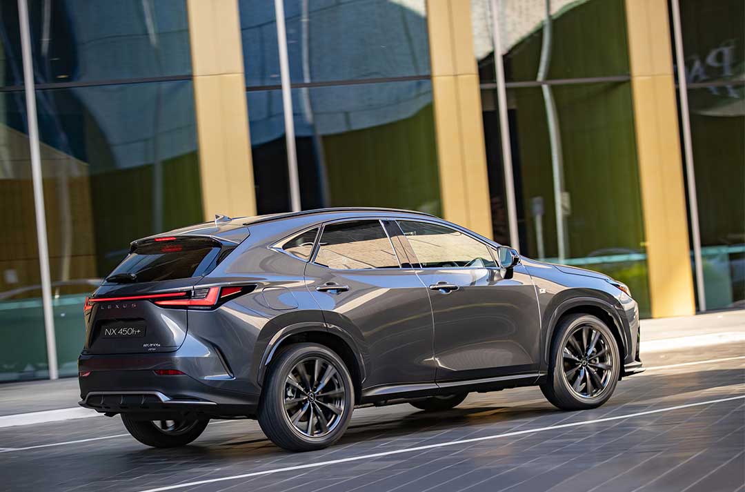 Lexus NX 450h+ drives along a road with yellow walls in the background.