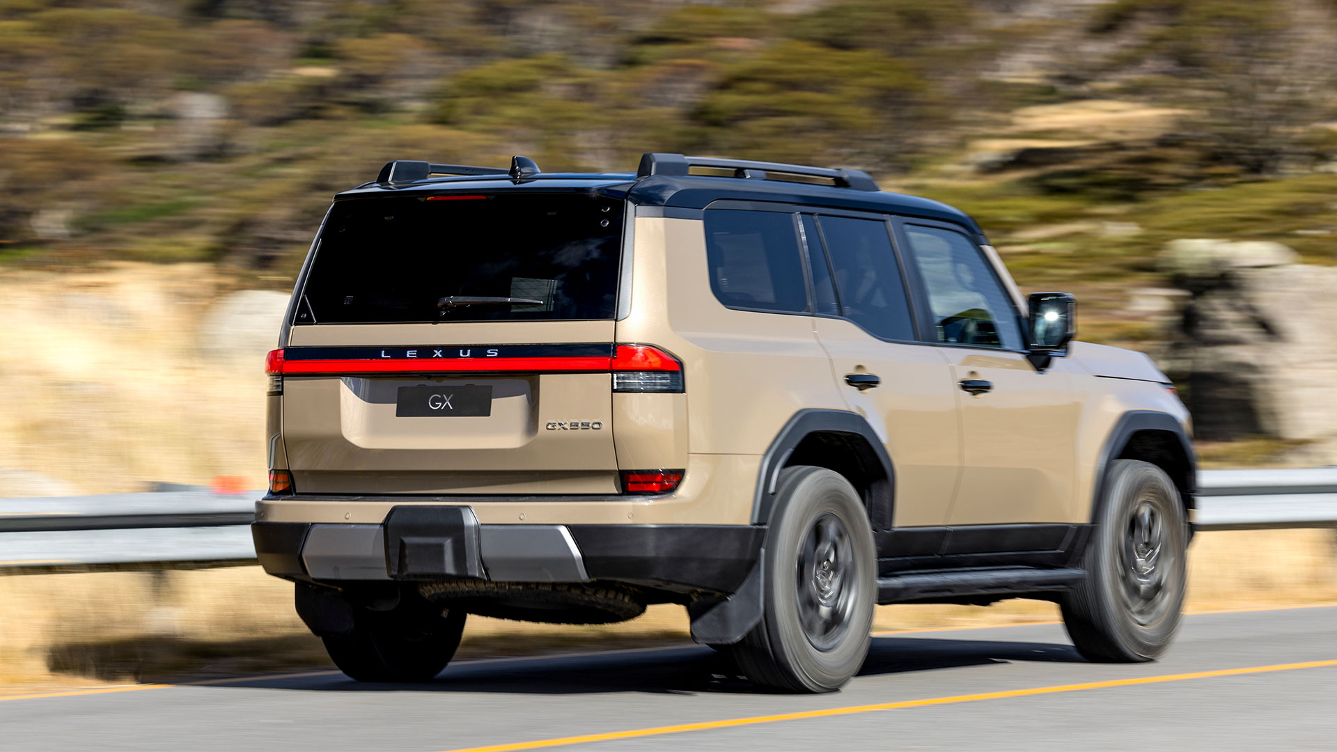An Earth toned Lexus GX driving with a background of greenery