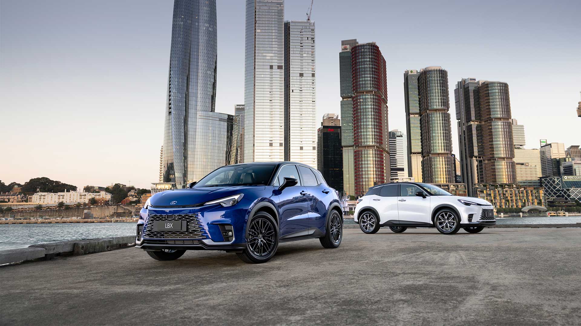 Blue and white Lexus LBX vehicles parked against a cityscape