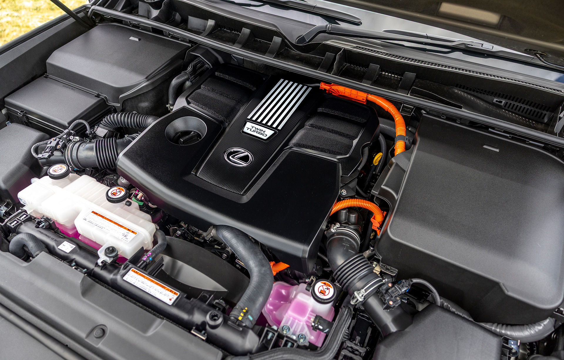 Close-up of a Lexus LX 700h engine bay featuring twin-turbo hybrid powertrain and high-voltage hybrid components.