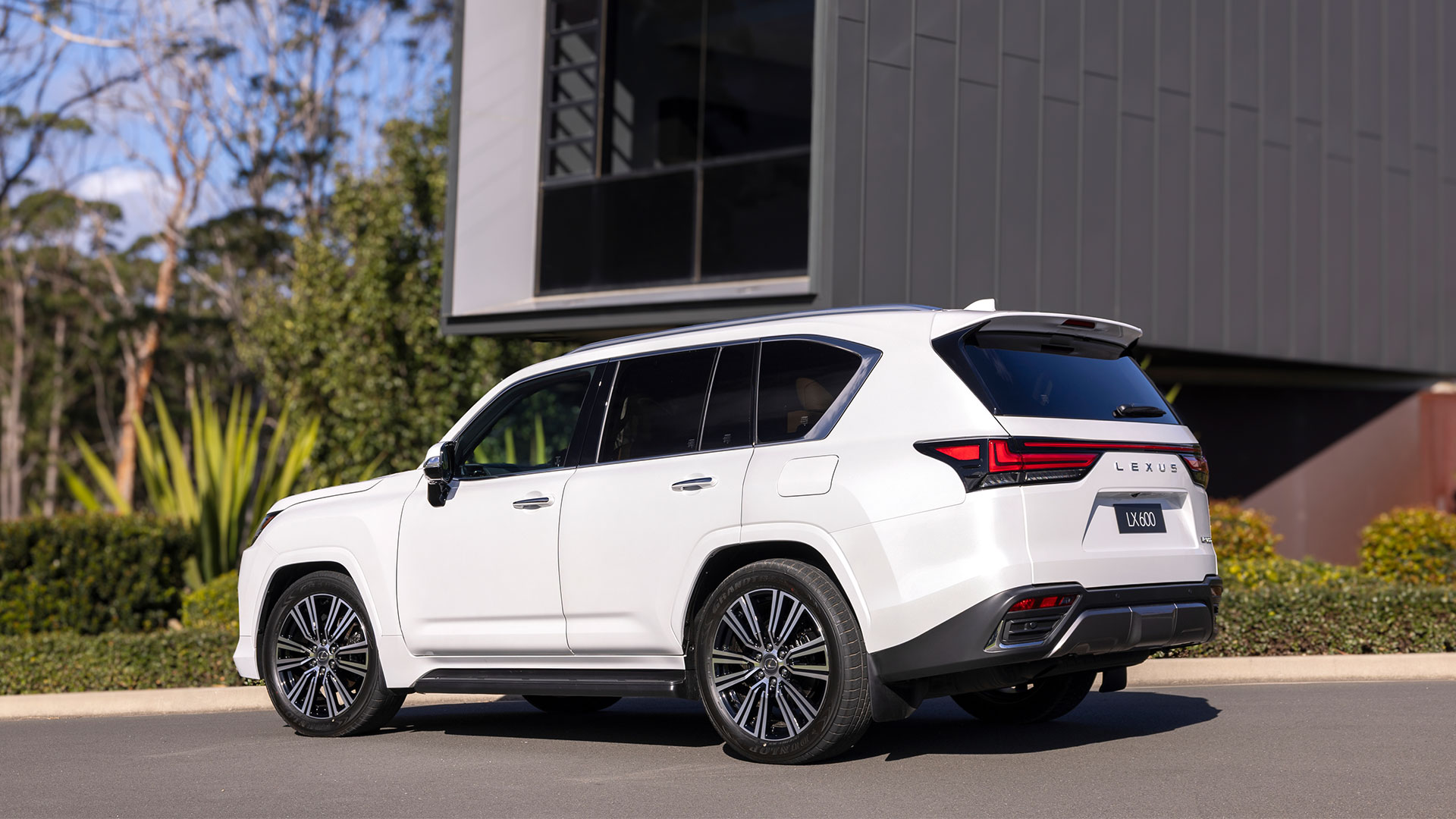 A white 2025 Lexus LX 600 Sports luxury parked outside a modern building