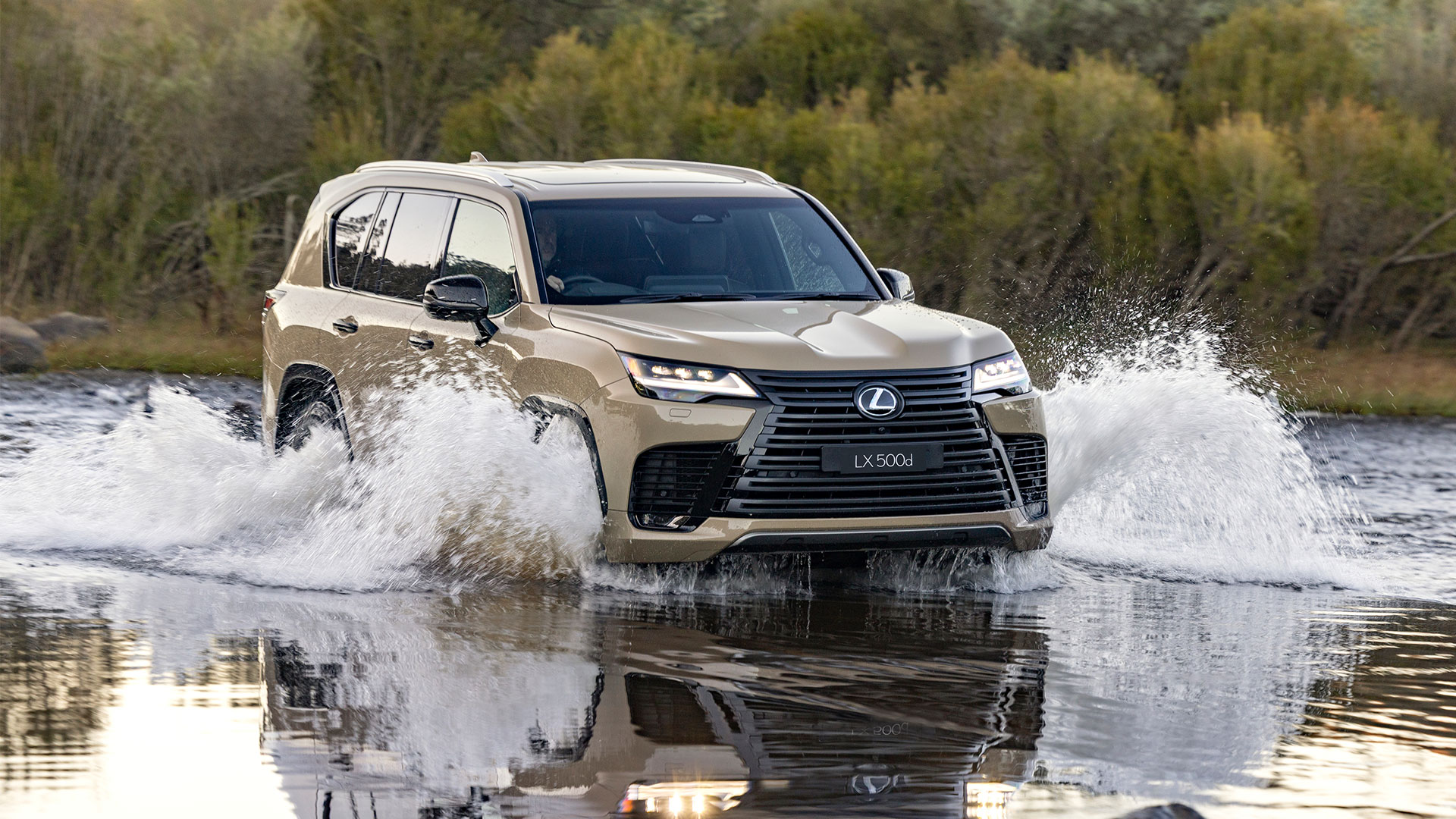 Lexus LX 500d Overtrail in Earth tone driving through shallow water in a natural landscape