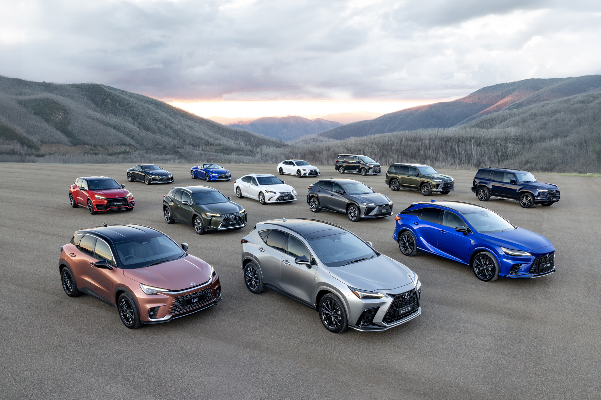 Lexus vehicle lineup including SUVs and sedans displayed on open landscape with mountain backdrop