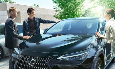 Three people gather around a black Lexus NX 250.